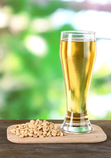 Cerveza en vaso y nueces sobre mesa sobre fondo natural — Foto de Stock