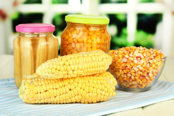 Fresh, canned and dried corn on wooden table, on bright background — Stock Photo, Image