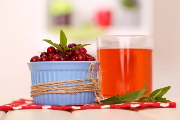 Glas tranbärsjuice och mogna röda tranbär i skål på bordet — Stockfoto