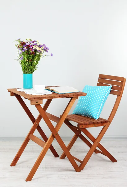 Dřevěný stůl s kytičkou, kniha a pohár na to v pokoji — Stock fotografie