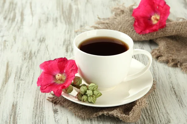 Чашка кави і рожеві квіти на дерев'яному фоні — стокове фото
