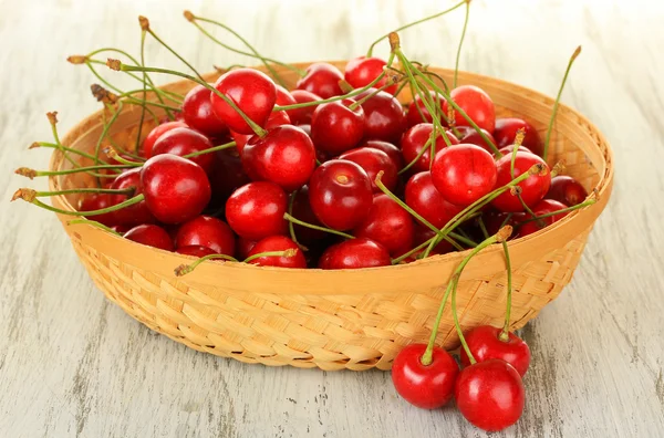 Cherry berries in wicker basket on wooden table close up — Stock Photo, Image