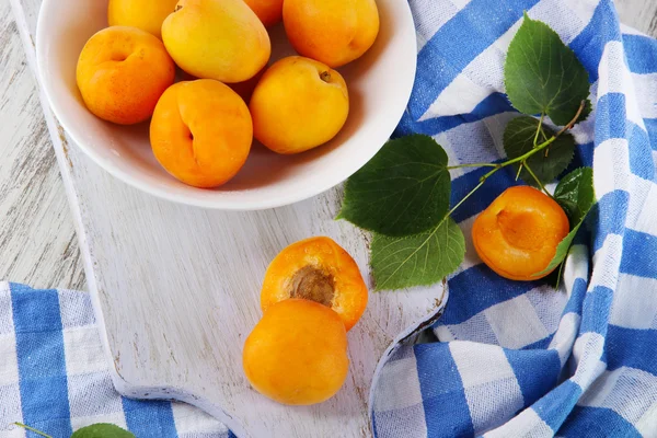 Apricots on board for cutting on napkin on wooden table — Stock Photo, Image