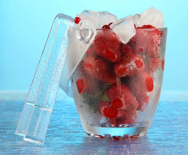 Gefrorene Beeren im Eimer mit Eis auf farbigem Hintergrund — Stockfoto