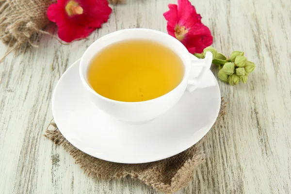 Cup of tea and pink mallow flowers on wooden background — Stock Photo, Image