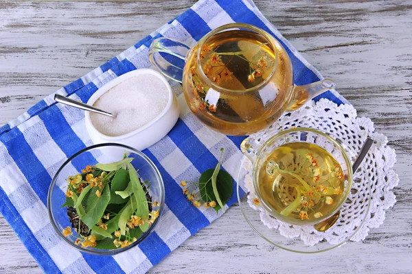 Bollitore e tazza di tè con tiglio sul tavolo di legno — Foto Stock