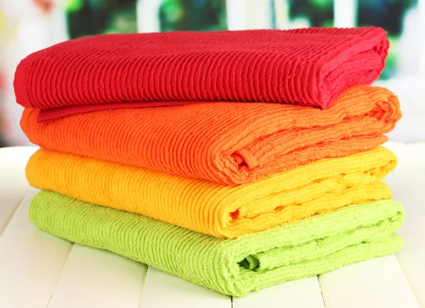 Colorful towels on wooden table on window background — Stock Photo, Image