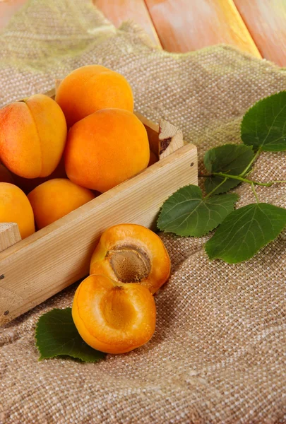 Abricots dans le tiroir sur l'ensachage sur une table en bois — Photo