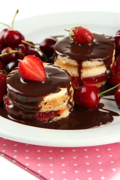 Tasty biscuit cakes with chocolate and berries on plate, close up — Stock Photo, Image