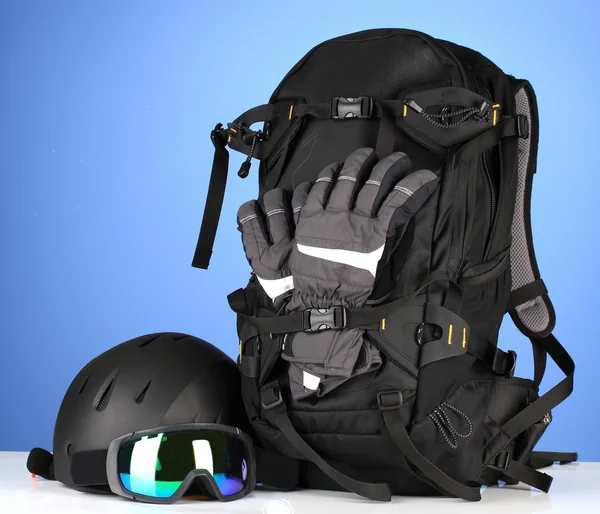 Wintersportbrille, Helm und Handschuhe, Rucksack, auf blauem Hintergrund — Stockfoto