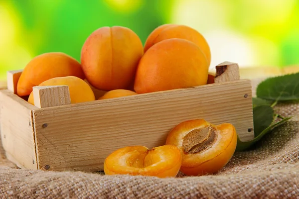 Apricots in drawer on bagging on wooden table on nature background — Stock Photo, Image