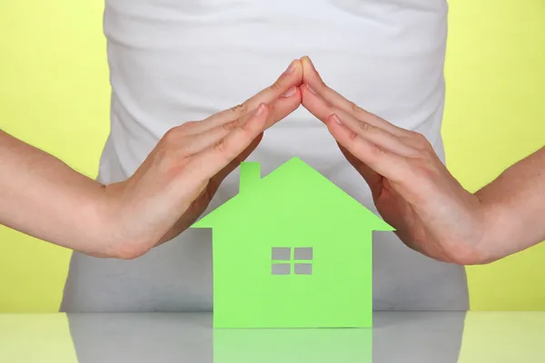 Papier huis in handen op groene achtergrond — Stockfoto