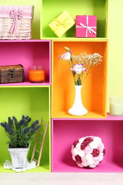 Regale in verschiedenen hellen Farben mit dekorativer Ergänzung auf Wandhintergrund — Stockfoto