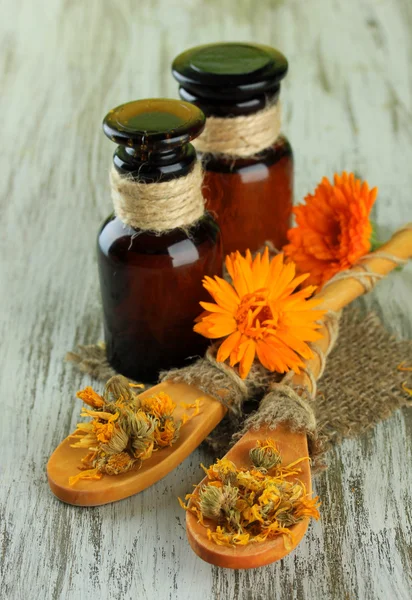 Medicine bottles and calendula flowers on wooden background — Stock Photo, Image