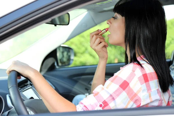 Mujer joven aplicando maquillaje en el coche — Foto de Stock