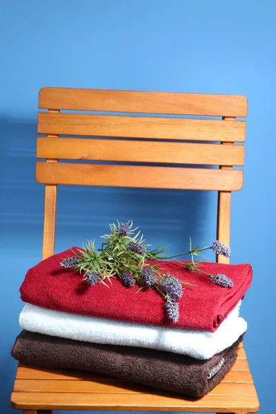 Serviettes et fleurs sur chaise en bois sur fond bleu — Photo