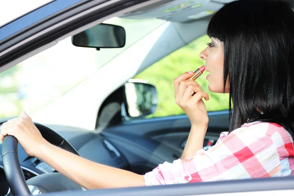 Mujer joven aplicando maquillaje en el coche — Foto de Stock