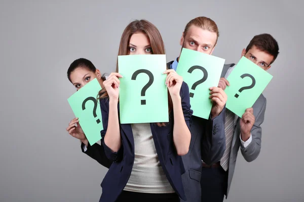 Business team standing in row with question mark on grey background — Stock Photo, Image