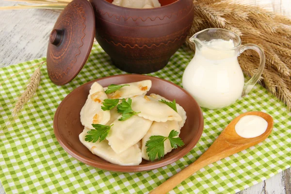 Tasty dumplings with fried onion on brown plate, on wooden background — Stock Photo, Image