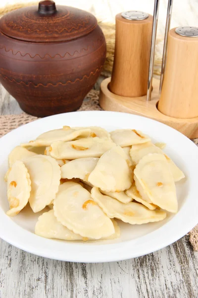 Tasty dumplings with fried onion on white plate, on wooden background — Stock Photo, Image