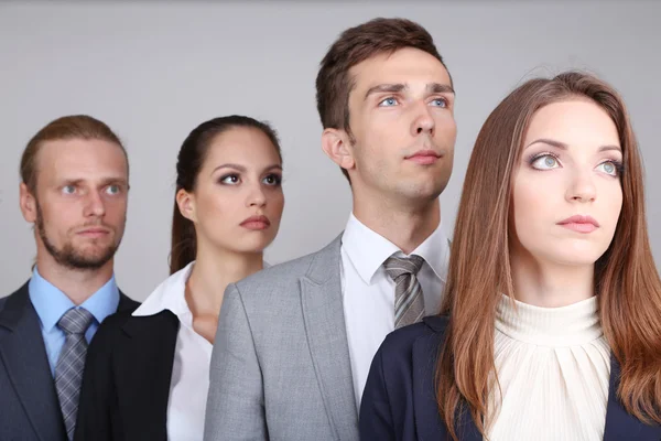 Бізнес команда, стоячи в ряд на сірому фоні — стокове фото