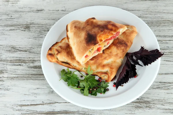 Pizza calzoni su piatto su tavolo di legno — Foto Stock