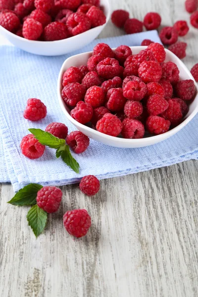 Framboises sucrées mûres dans des bols sur fond de bois — Photo