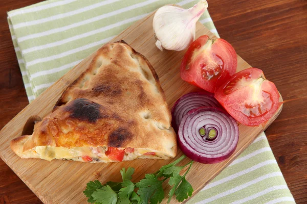 Pizza calzone su tavola di legno su tovagliolo su tavolo di legno — Foto Stock