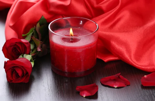 Красная свеча с цветами и шелковой тканью, крупным планом — стоковое фото