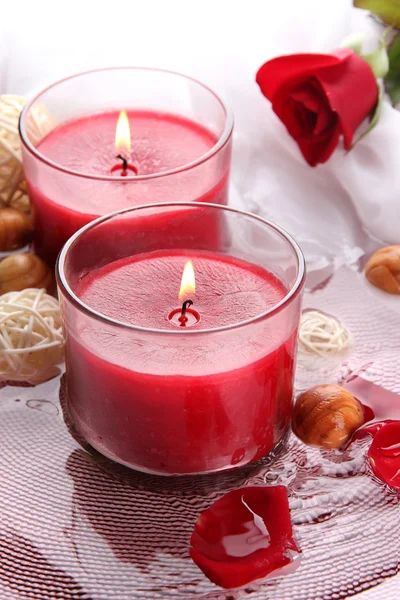 Schöne rote Kerzen mit Blütenblättern im Wasser — Stockfoto