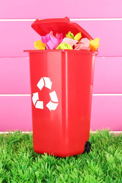 Corbeille de recyclage avec papiers sur gazon sur fond rose — Photo