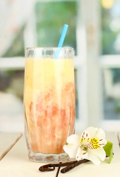 Delicious fruit smoothie on wooden table on window background — Stock Photo, Image