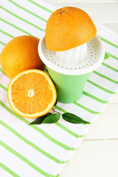 Prensa cítrica y naranjas maduras sobre mesa de madera blanca — Foto de Stock