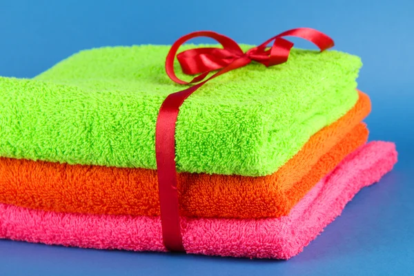 Towels tied with ribbon on blue background — Stock Photo, Image