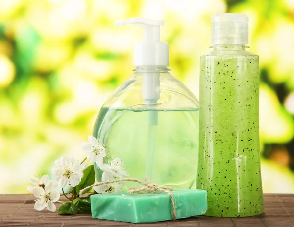 Косметичні пляшки та натуральне мило ручної роботи на зеленому фоні — стокове фото