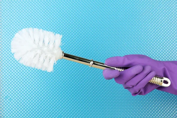 Toilet brush in hand on blue background — Stock Photo, Image