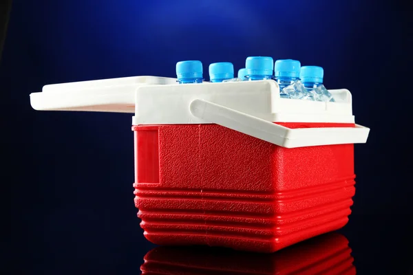 Refrigerador viajero con botellas de agua y cubitos de hielo, sobre fondo azul — Foto de Stock