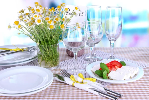 Table setting with chamomiles on checkered tablecloth on window background — Stock Photo, Image