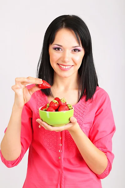 Hermosa joven con fresas sobre fondo gris —  Fotos de Stock