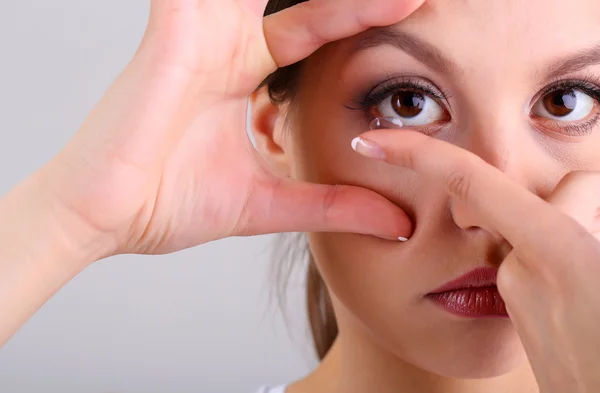 Young woman putting contact lens in her eye close up — Stock Photo, Image