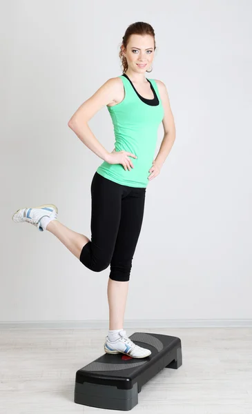 Beautiful young woman exercises on stepper — Stock Photo, Image
