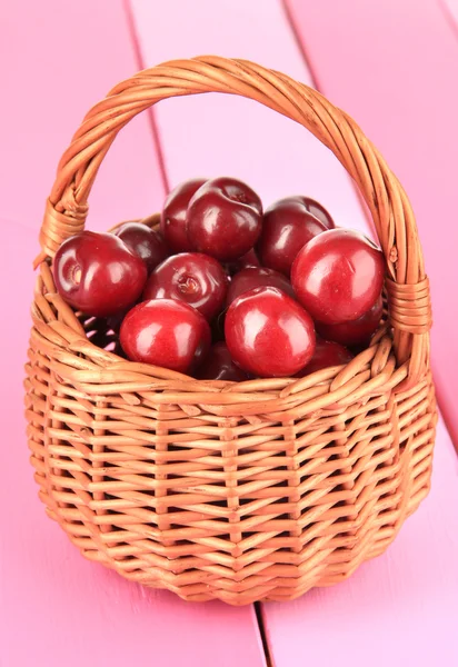 Cherry berries in wicker basket on wooden table close-up — Stock Photo, Image