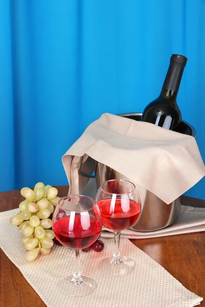 Vinho e copos na mesa redonda sobre pano de fundo — Fotografia de Stock