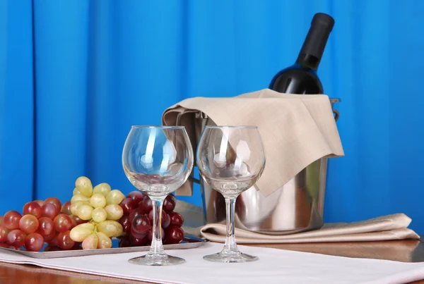 Vin och glasögon på runda bordet på duk bakgrund — Stockfoto