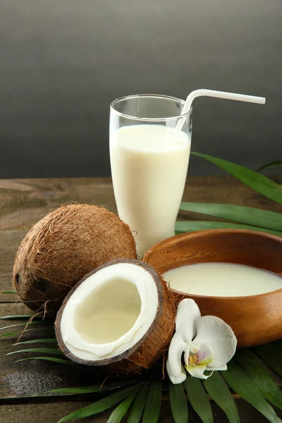 Coco con vaso de leche, sobre mesa de madera, sobre fondo gris —  Fotos de Stock