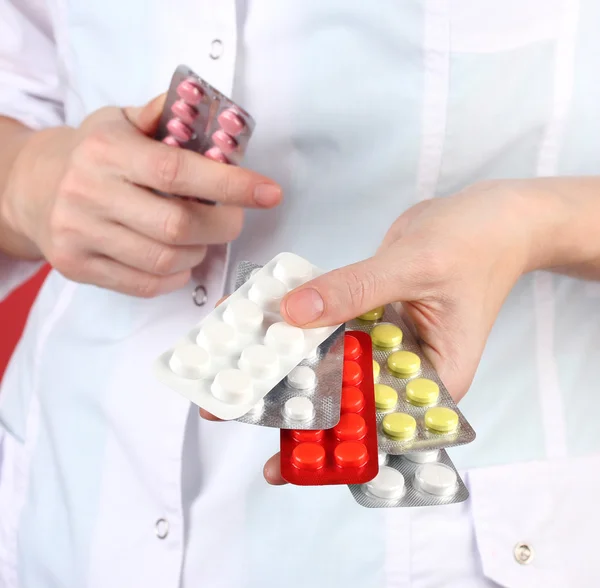 Close-up of female doctor hand holding pills, on color background — Stock Photo, Image