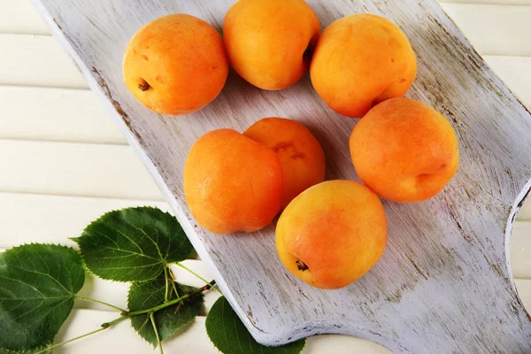 Apricots on board on wooden table — Stock Photo, Image