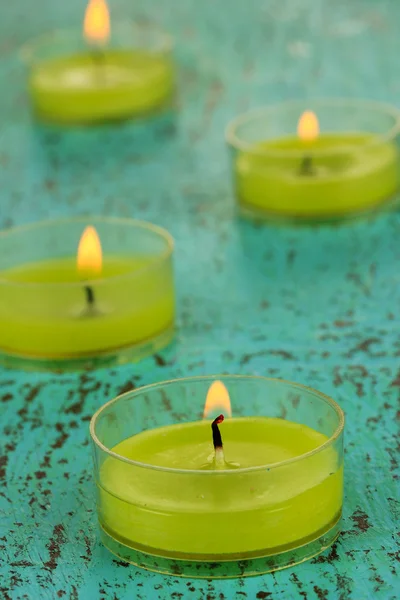 Зажженные свечи с бусами на зеленом фоне — стоковое фото