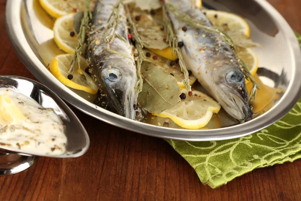 Fish in frying pan with spices and lemon on wooden table close-up — Stock Photo, Image