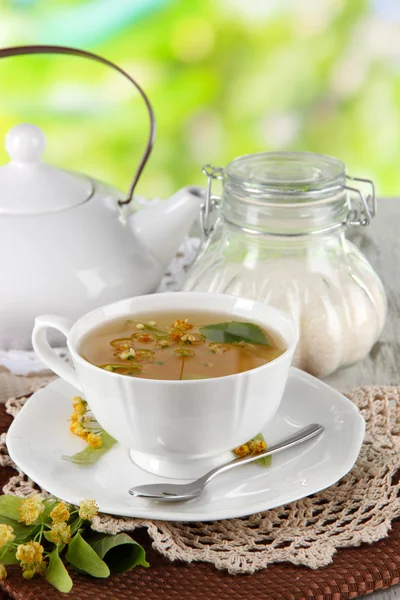 Kopje thee met linden op servetten op houten tafel op aard achtergrond — Stockfoto